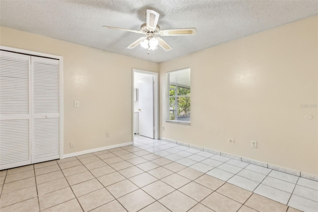 896 Satin Leaf Cir, Ocoee, FL 34761 - unfurnished bedroom featuring a textured ceiling, a closet, light tile patterned flooring, a ceiling fan, and baseboards