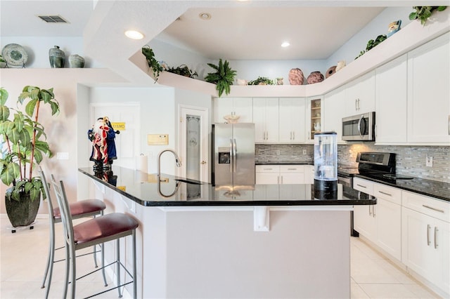 10642 Cloudview Dr, Orlando, FL 32825 - kitchen with appliances with stainless steel finishes, a breakfast bar, dark countertops, tasteful backsplash, and a spacious island