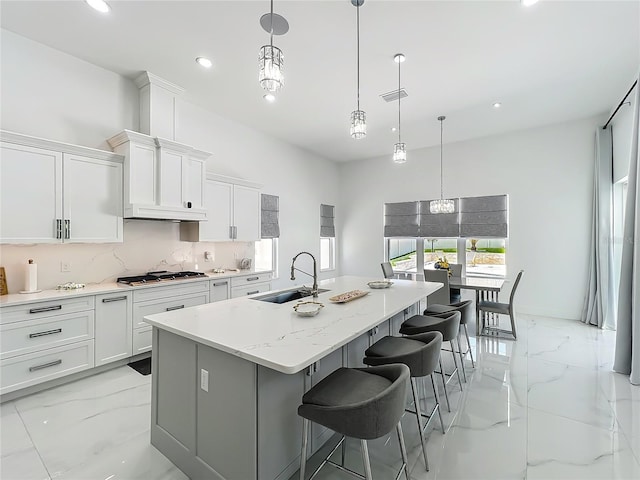 601 Green Briar Blvd, Altamonte Springs, FL 32714 - kitchen with a sink, stainless steel gas stovetop, a kitchen island with sink, light marble finish floors, and white cabinets