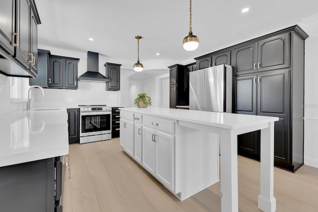 2460 Worthington Rd, Maitland, FL 32751 - kitchen featuring wall chimney range hood, stainless steel appliances, a sink, light countertops, and light wood finished floors