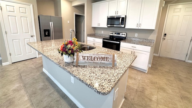2450 Sweet Viburnum Way, Ocoee, FL 34761 - kitchen with appliances with stainless steel finishes, white cabinetry, light stone counters, a center island with sink, and baseboards