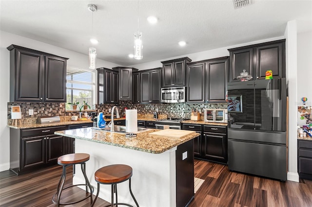 14095 Tropical Kingbird Way, Riverview, FL 33579 - kitchen with appliances with stainless steel finishes, dark wood-style flooring, a sink, an island with sink, and recessed lighting