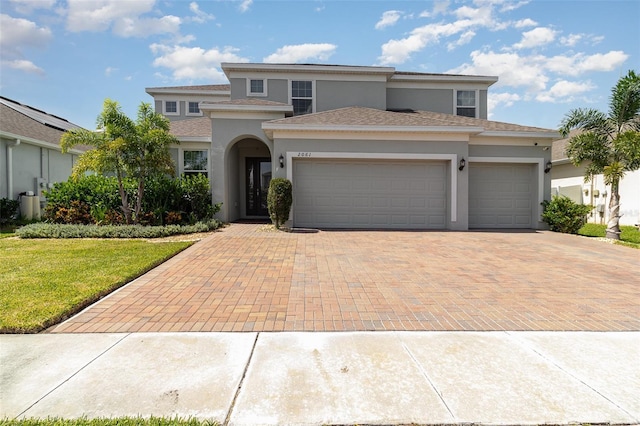 2061 Rush Bay Way, Orlando, FL 32824 - view of front of house featuring stucco siding, decorative driveway, an attached garage, a front lawn, and a shingled roof