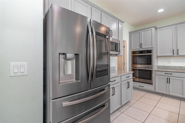 2061 Rush Bay Way, Orlando, FL 32824 - kitchen with appliances with stainless steel finishes, gray cabinetry, light tile patterned flooring, and light stone counters