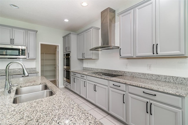 2061 Rush Bay Way, Orlando, FL 32824 - kitchen featuring appliances with stainless steel finishes, wall chimney range hood, gray cabinetry, light tile patterned floors, and light stone countertops