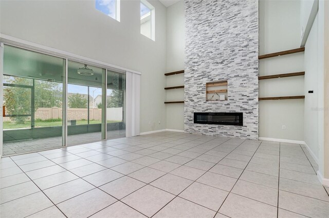 2061 Rush Bay Way, Orlando, FL 32824 - unfurnished living room featuring a towering ceiling, a fireplace, and light tile patterned floors