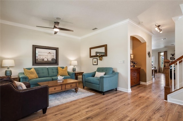 402 S Lake Victoria Cir, Deland, FL 32724 - living room featuring arched walkways, light wood-style floors, a ceiling fan, stairs, and crown molding
