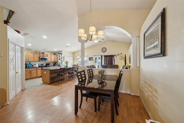 2354 Barons Ct, Tavares, FL 32778 - dining space featuring vaulted ceiling, arched walkways, a chandelier, light wood-style flooring, and decorative columns
