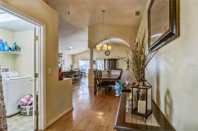 2354 Barons Ct, Tavares, FL 32778 - hall with washer / dryer, vaulted ceiling, a chandelier, light wood-type flooring, and baseboards