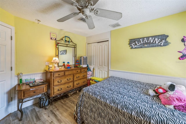 2354 Barons Ct, Tavares, FL 32778 - bedroom with wood finished floors, wainscoting, a closet, a textured ceiling, and a ceiling fan