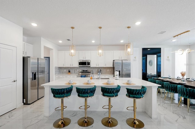 3860 Sonoma Blvd, Kissimmee, FL 34741 - kitchen featuring appliances with stainless steel finishes, tasteful backsplash, light marble finish flooring, a large island with sink, and white cabinets