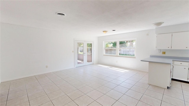 1119 Edith Dr, Daytona Beach, FL 32117 - kitchen with french doors, white cabinets, light tile patterned floors, a peninsula, and light countertops
