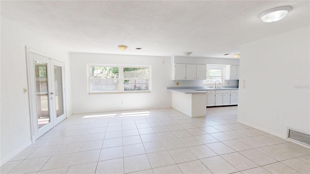 1119 Edith Dr, Daytona Beach, FL 32117 - kitchen featuring a peninsula, white cabinets, light countertops, light tile patterned floors, and open floor plan