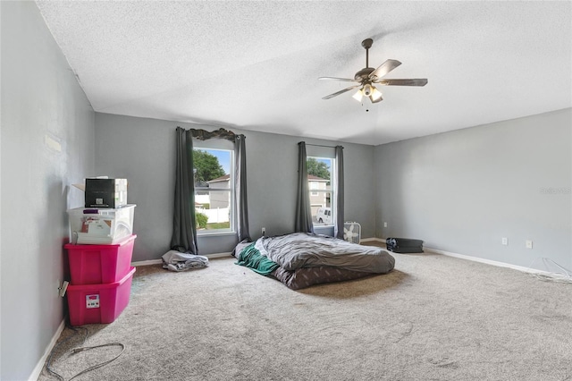 bedroom featuring a textured ceiling, carpet floors, baseboards, and ceiling fan