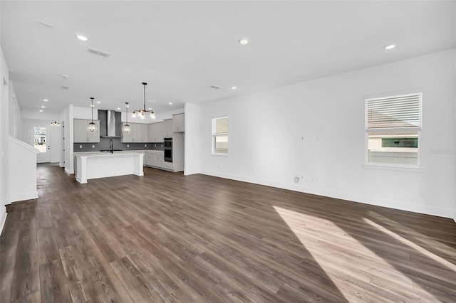 13081 Sunrise Harvest Dr, Winter Garden, FL 34787 - unfurnished living room featuring a sink, a chandelier, recessed lighting, dark wood-style floors, and baseboards