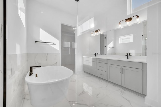 13081 Sunrise Harvest Dr, Winter Garden, FL 34787 - full bath with double vanity, a freestanding tub, marble finish floors, a wainscoted wall, and tile walls