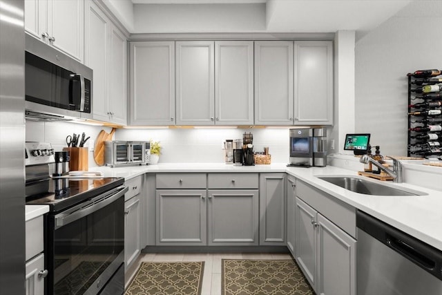 1 Riverwalk Dr Unit 303, New Smyrna Beach, FL 32169 - kitchen featuring appliances with stainless steel finishes, gray cabinets, a sink, light countertops, and light tile patterned floors