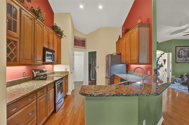 4571 Abaco Dr, Tavares, FL 32778 - kitchen featuring stainless steel appliances, a sink, dark stone countertops, light wood-type flooring, and high vaulted ceiling