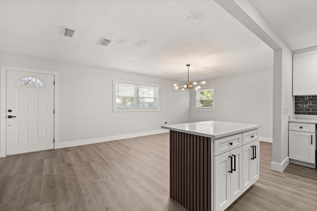 612 Florida Ave, Saint Cloud, FL 34769 - kitchen featuring light wood-type flooring, light countertops, white cabinets, and baseboards
