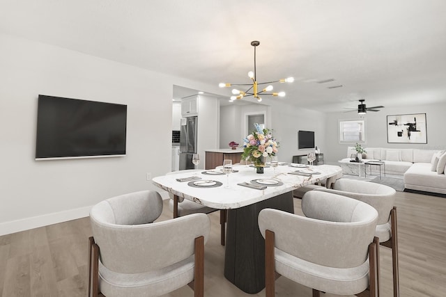 612 Florida Ave, Saint Cloud, FL 34769 - dining space with a chandelier, light wood-style flooring, a ceiling fan, and baseboards
