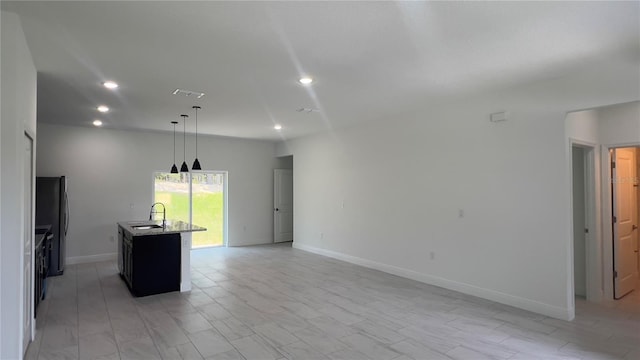 3315 W Montgomery Ln, Citrus Springs, FL 34433 - kitchen featuring a sink, freestanding refrigerator, an island with sink, recessed lighting, and light stone counters