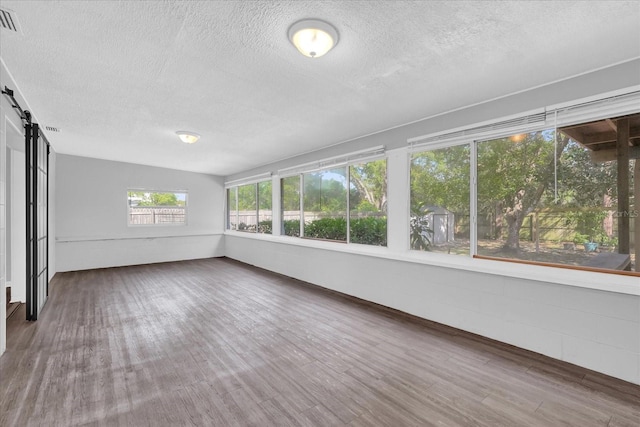 2357 E Dana Dr, Deltona, FL 32738 - unfurnished sunroom featuring a textured ceiling, a barn door, and wood finished floors