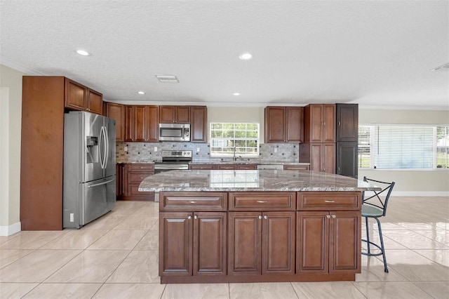 181 W Minnehaha Ave, Clermont, FL 34711 - kitchen with stainless steel appliances, crown molding, a kitchen island, a sink, and baseboards