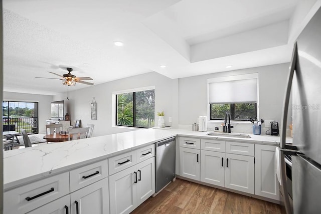5800 N Banana River Blvd Unit 128, Cape Canaveral, FL 32920 - kitchen featuring a sink, appliances with stainless steel finishes, light stone counters, ceiling fan, and wood finished floors