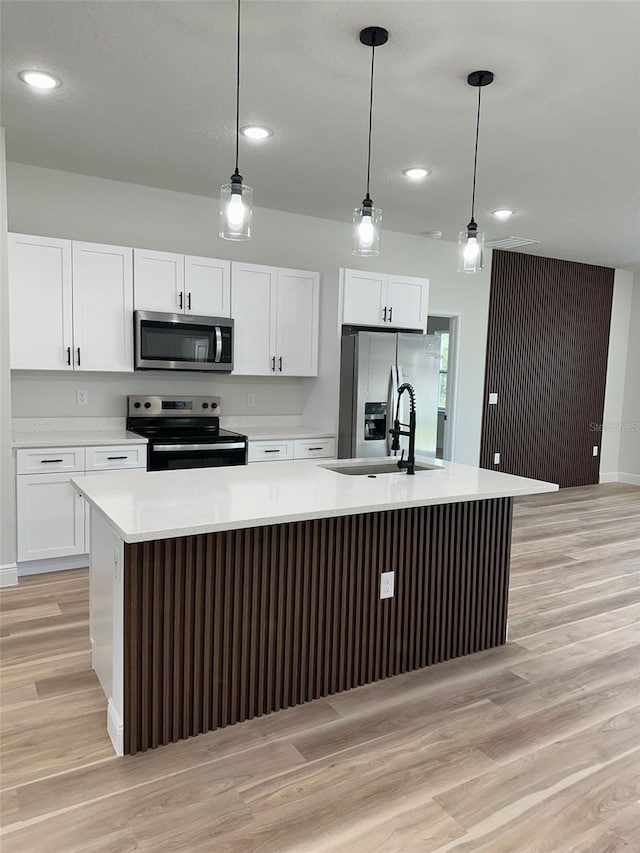 3063 SW 168th Loop, Ocala, FL 34473 - kitchen with appliances with stainless steel finishes, an island with sink, light wood-style floors, a sink, and white cabinetry