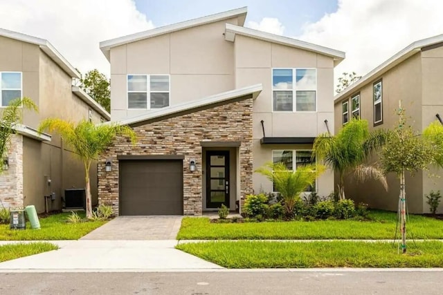 671 Drop Shot Dr, Davenport, FL 33896 - modern home featuring stone siding, concrete driveway, cooling unit, stucco siding, and an attached garage
