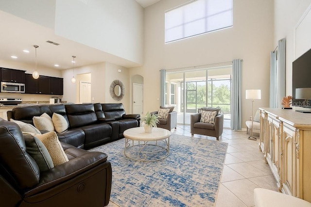 living room with light tile patterned flooring, a towering ceiling, and arched walkways