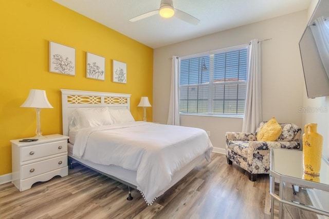 bedroom with light wood finished floors, baseboards, and ceiling fan