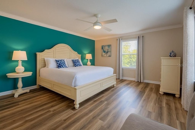 bedroom featuring crown molding, baseboards, wood finished floors, and a ceiling fan