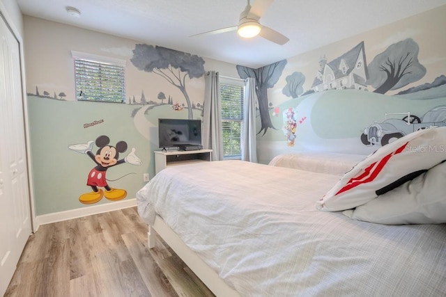 bedroom featuring wood finished floors, a ceiling fan, a closet, and baseboards