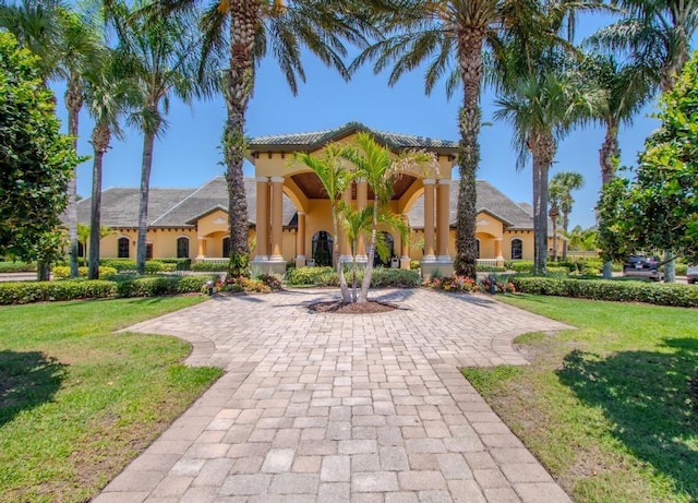 mediterranean / spanish-style house featuring a front lawn, stucco siding, and a tiled roof