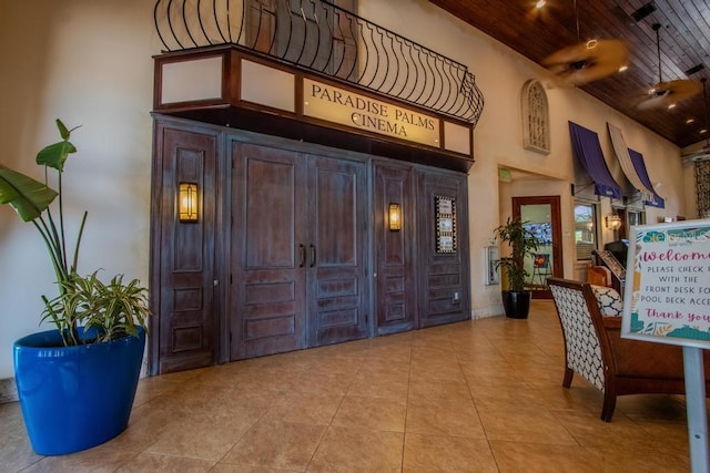 entryway with wooden ceiling, a towering ceiling, and light tile patterned floors