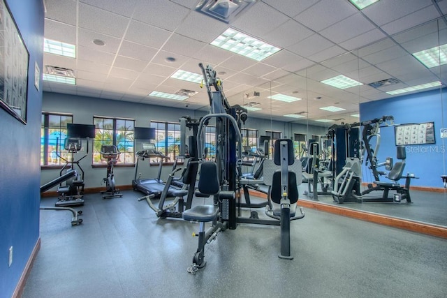 exercise room with baseboards and a drop ceiling