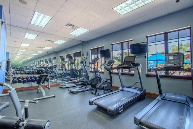 exercise room with a paneled ceiling and baseboards