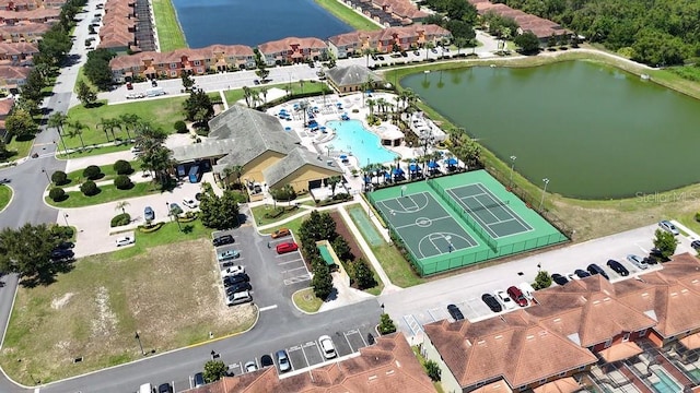 aerial view of property and surrounding area with a nearby body of water and a pool area
