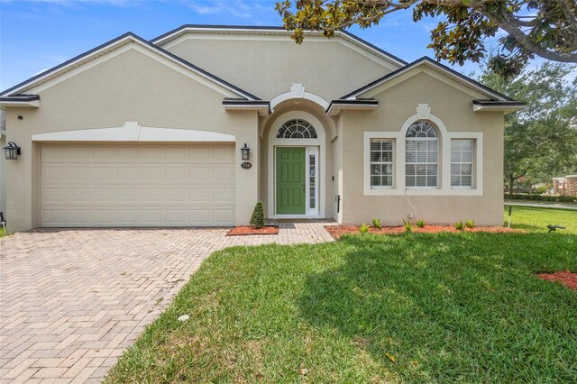 714 Home Grove Dr, Winter Garden, FL 34787 - view of front of property featuring stucco siding, decorative driveway, a front yard, and an attached garage