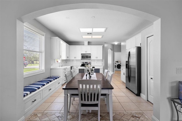 714 Home Grove Dr, Winter Garden, FL 34787 - dining area featuring washer / clothes dryer, arched walkways, and light tile patterned floors