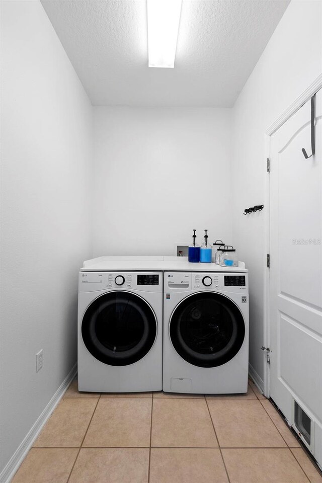 714 Home Grove Dr, Winter Garden, FL 34787 - laundry room with independent washer and dryer, light tile patterned floors, a textured ceiling, and baseboards