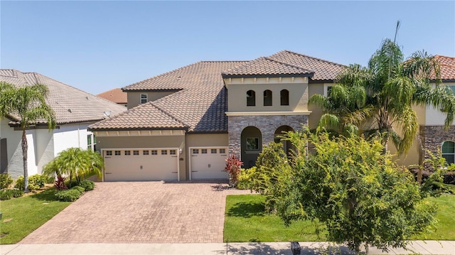 8419 Pippen Dr, Orlando, FL 32836 - mediterranean / spanish house featuring stucco siding, an attached garage, decorative driveway, stone siding, and a tiled roof