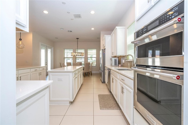 8419 Pippen Dr, Orlando, FL 32836 - kitchen featuring a sink, stainless steel appliances, a kitchen island, light tile patterned floors, and white cabinetry
