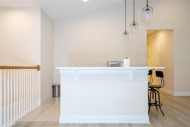 8419 Pippen Dr, Orlando, FL 32836 - kitchen with a breakfast bar area, baseboards, an island with sink, hanging light fixtures, and light wood-style flooring