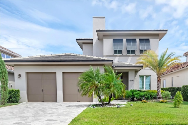 15947 Vetta Dr, Bella Collina, FL 34756 - prairie-style home with an attached garage, stucco siding, decorative driveway, a front yard, and a chimney