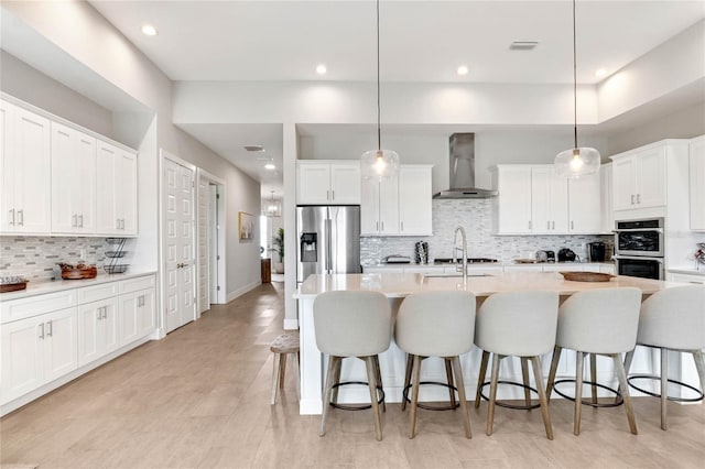 15947 Vetta Dr, Bella Collina, FL 34756 - kitchen featuring wall chimney exhaust hood, stainless steel appliances, decorative backsplash, a breakfast bar area, and recessed lighting