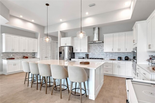 15947 Vetta Dr, Bella Collina, FL 34756 - kitchen featuring wall chimney range hood, stainless steel appliances, tasteful backsplash, a kitchen island with sink, and a kitchen bar