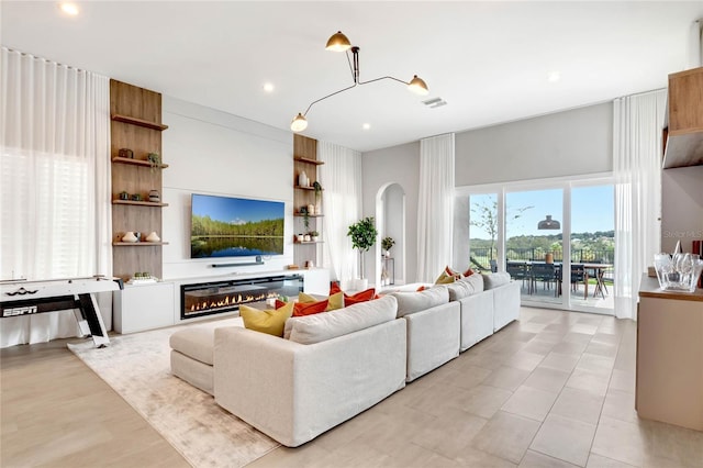 15947 Vetta Dr, Bella Collina, FL 34756 - living room with arched walkways, a glass covered fireplace, and recessed lighting