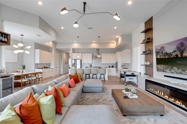 15947 Vetta Dr, Bella Collina, FL 34756 - living area with wine cooler, a glass covered fireplace, a chandelier, and recessed lighting